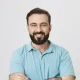 Smiling man in blue shirt with arms crossed