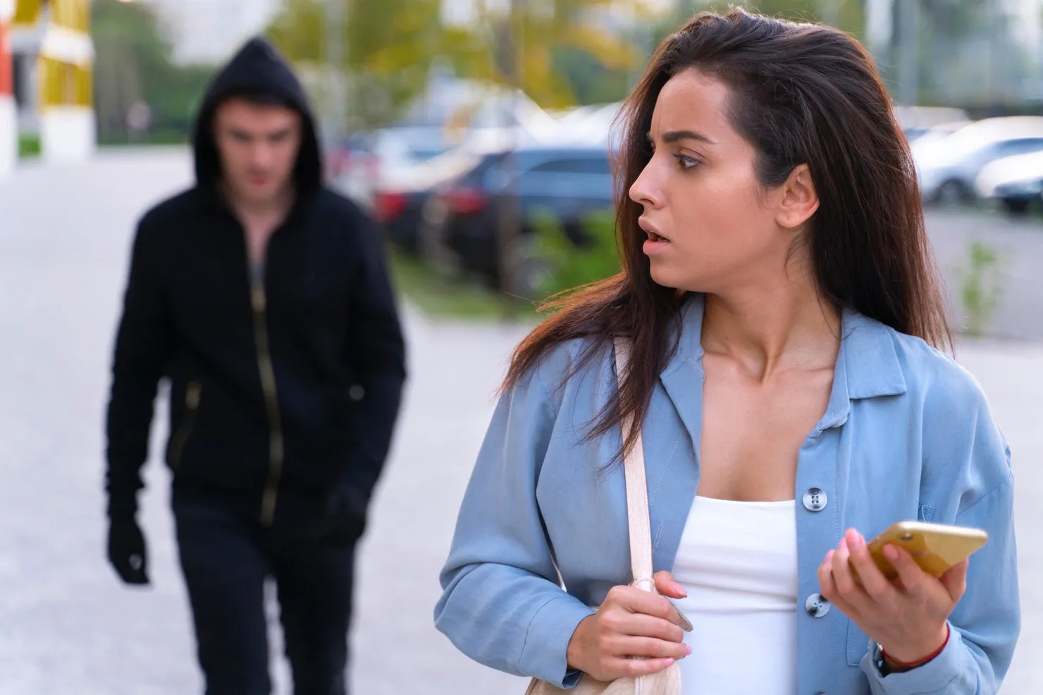 Woman looking concerned as man follows her, representing uttering threats