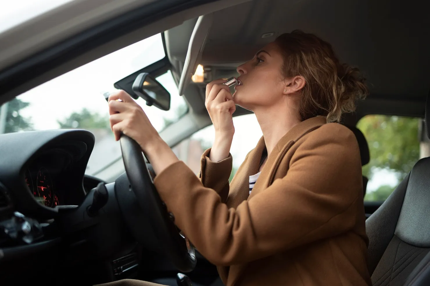 Careless Driving Woman applying lipstick while driving, representing careless driving.