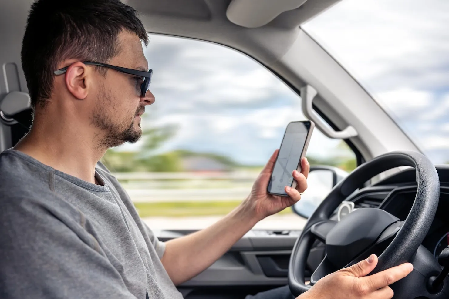 Distracted Driving Hand-held Devices Driver using phone while driving, representing distracted driving with hand-held device.