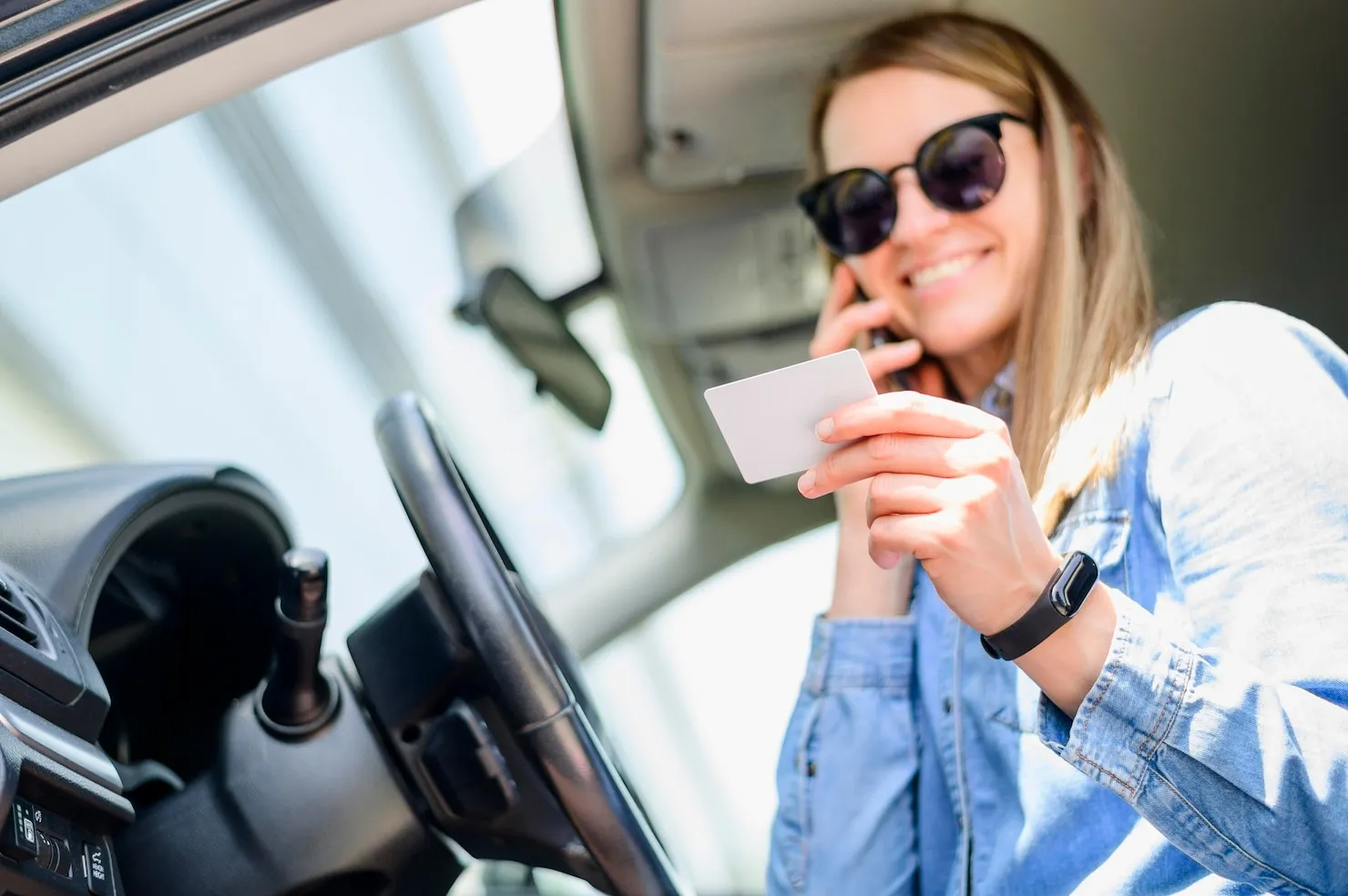 Speeding Tickets Driver holding card and talking on phone in car, representing speeding tickets.